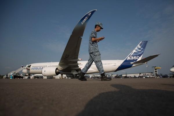 A soldier walks past an Airbus SAS A350 XWB flight test aircraft (MSN3) displayed at the Singapore Airshow held at the Changi Exhibition Centre in Singapore, on Feb. 11, 2014.