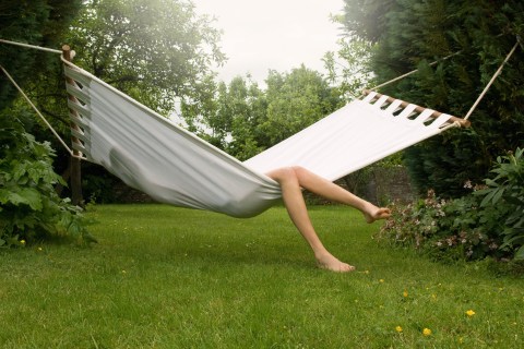 Female relaxing in hammock over lawn