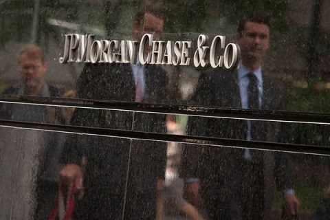 Commuters are reflected in stone as they walk past the JP Morgan headquarters in New York
