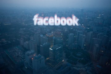 image: A computer screen displaying the logo of social networking site Facebook reflected in a window before the Beijing skyline, May 16, 2012 .