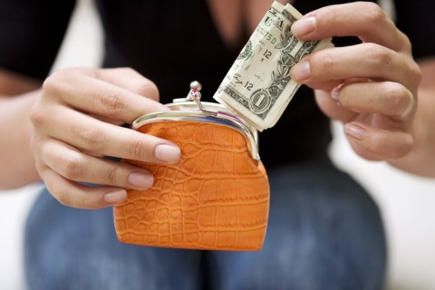 Woman putting a US  bill into a purse