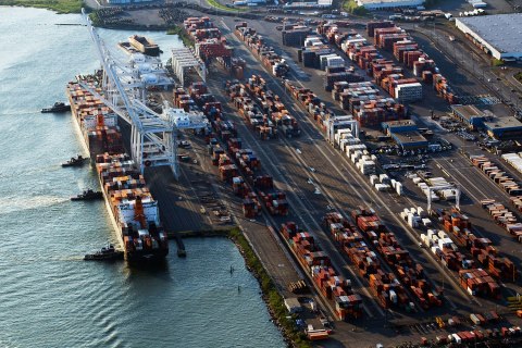 Tug boats maneuver cargo ships, one of which is onto their docks in Bayonne, N.J., on Aug. 24, 2011.