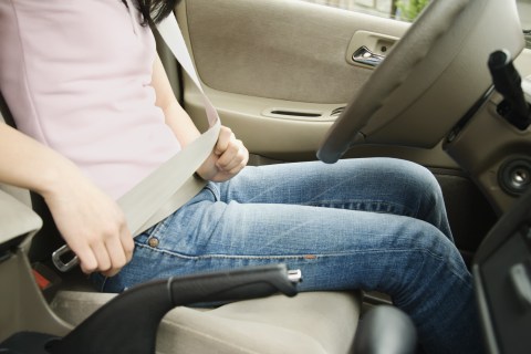 Teenager putting on seat belt