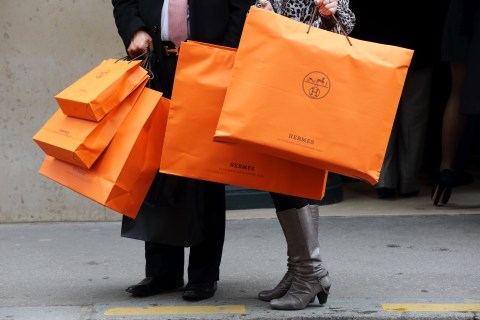 A couple walk with Hermes shopping bags as they leave an Hermes store in Paris
