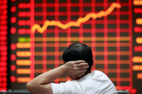 An investor looks at an electronic board showing stock information at a brokerage house in Huaibei