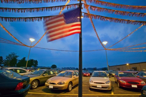 New and used cars in dealership parking lot, dusk 